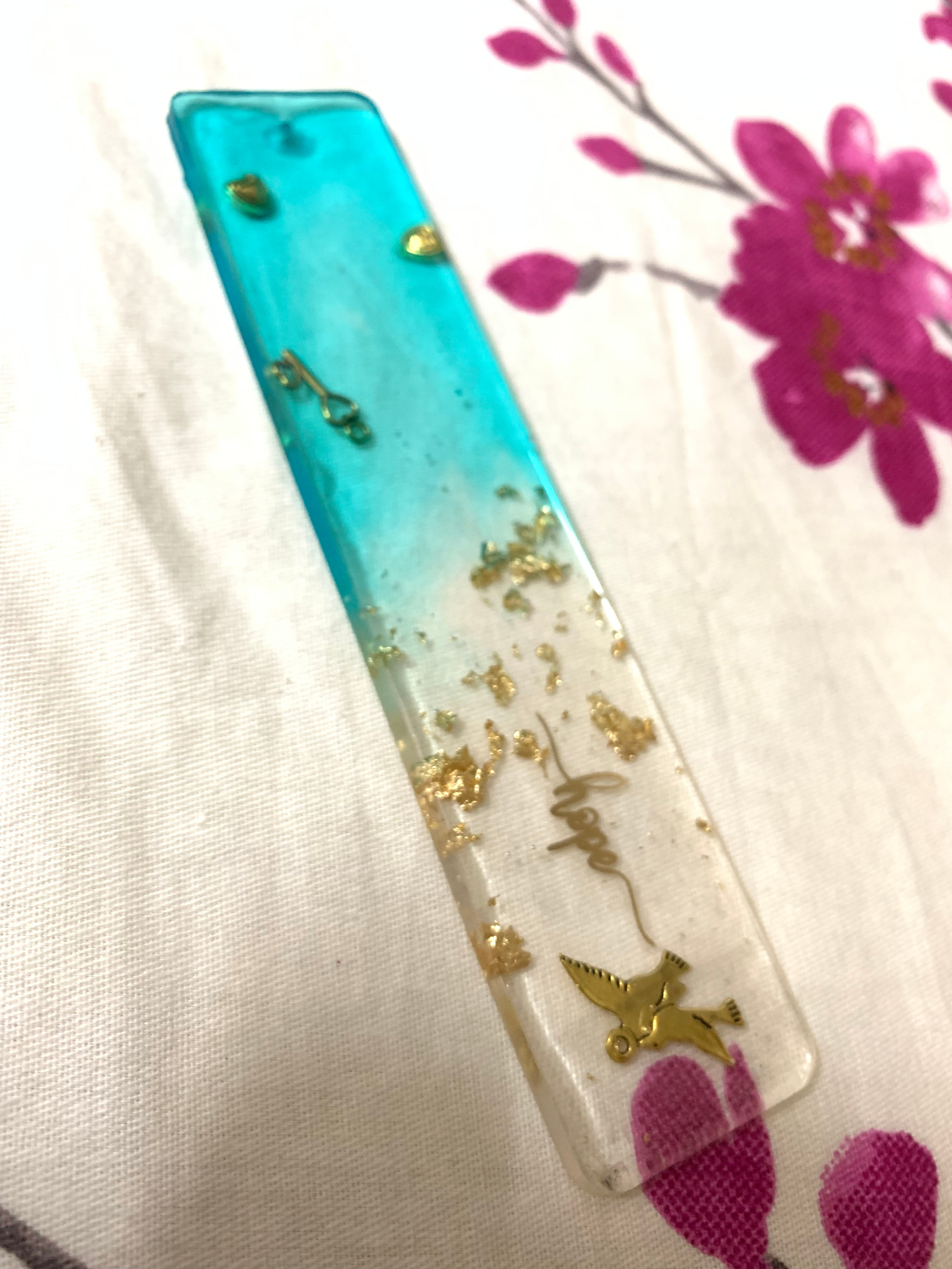 Teal and clear resin bookmark with gold flakes and the word 'hope' in gold script