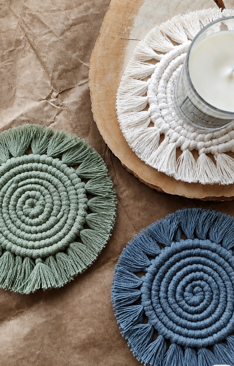 Pair of sage green and denim blue fringed macramé coasters with a candle