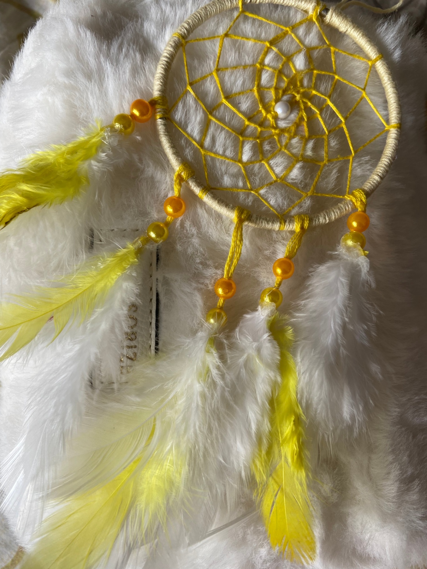 Small yellow dream catcher with yellow feathers and orange beads
