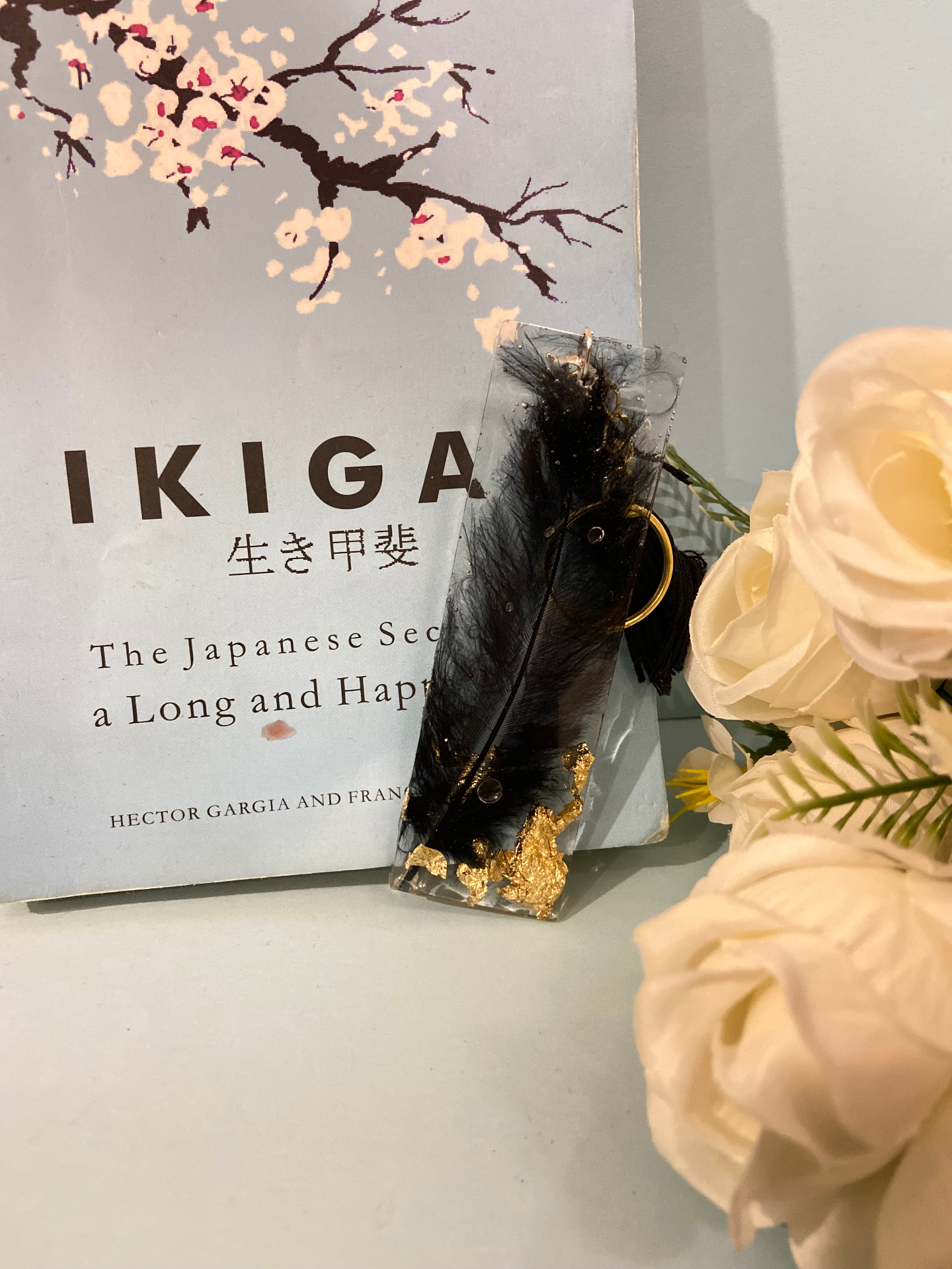 Clear resin bookmark with a black feather, gold flakes and black tassel