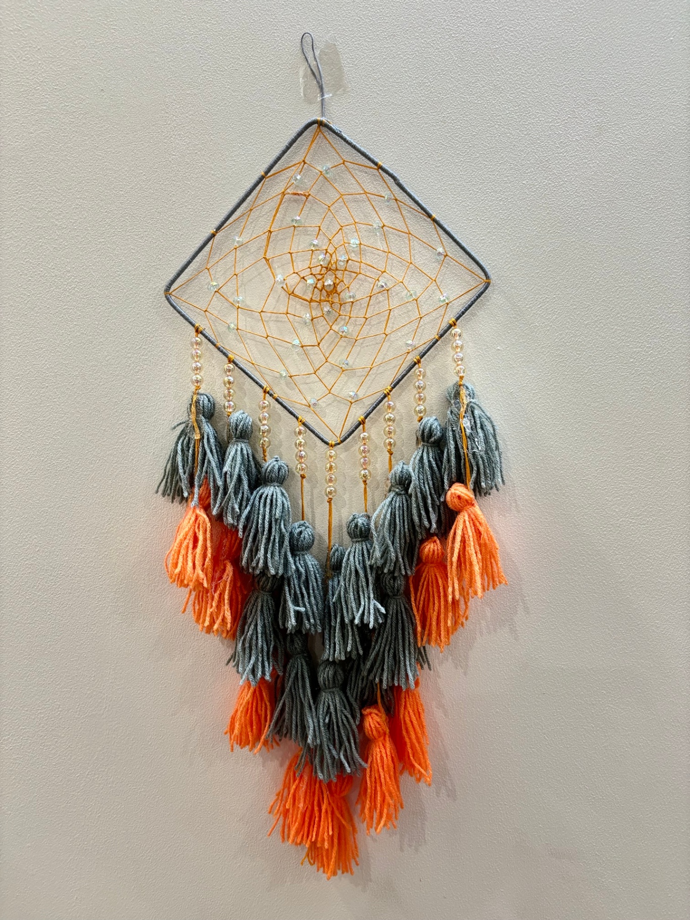 Diamond dream catcher with grey and orange yarn tassels and pearl beads