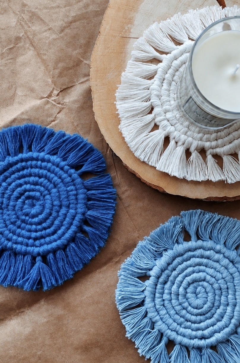 Pair of royal blue and powder blue fringed macramé coasters with a candle